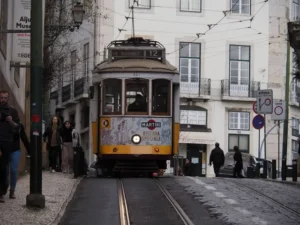 Yellow tram climbing a hill in Lisbon's Alfama district