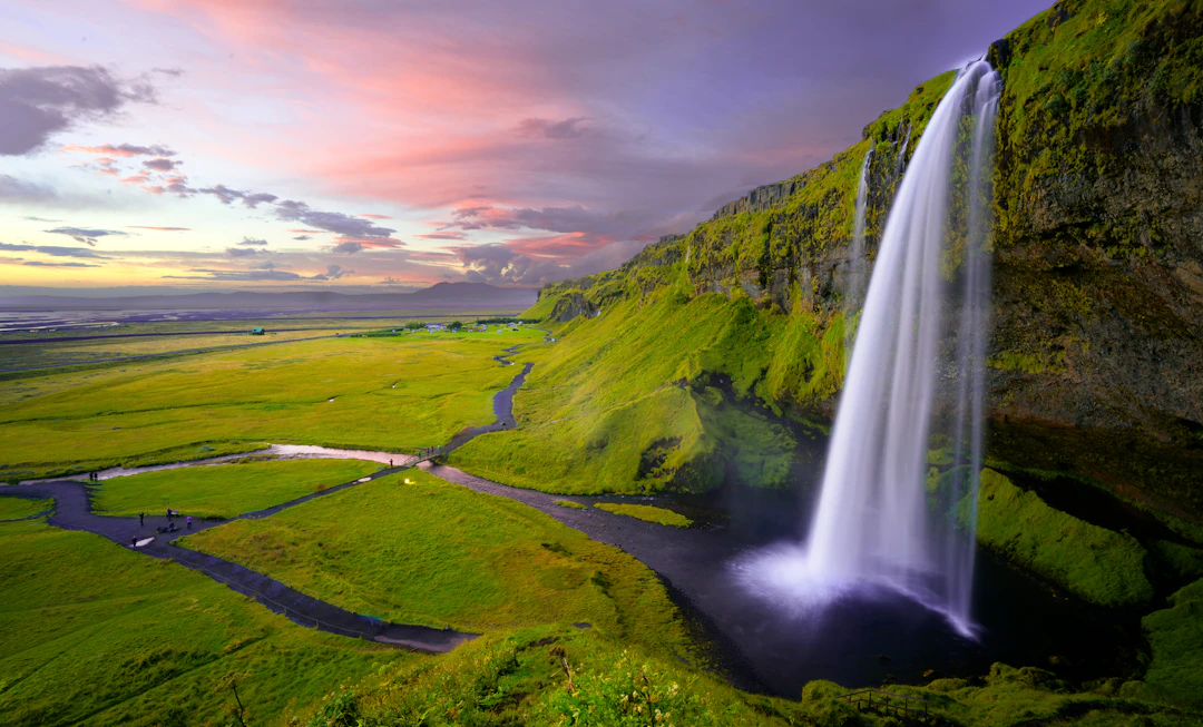 Waterfall cascading through green Icelandic landscape in summer